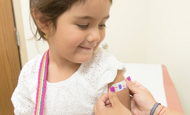 young girl receiving jab sticker