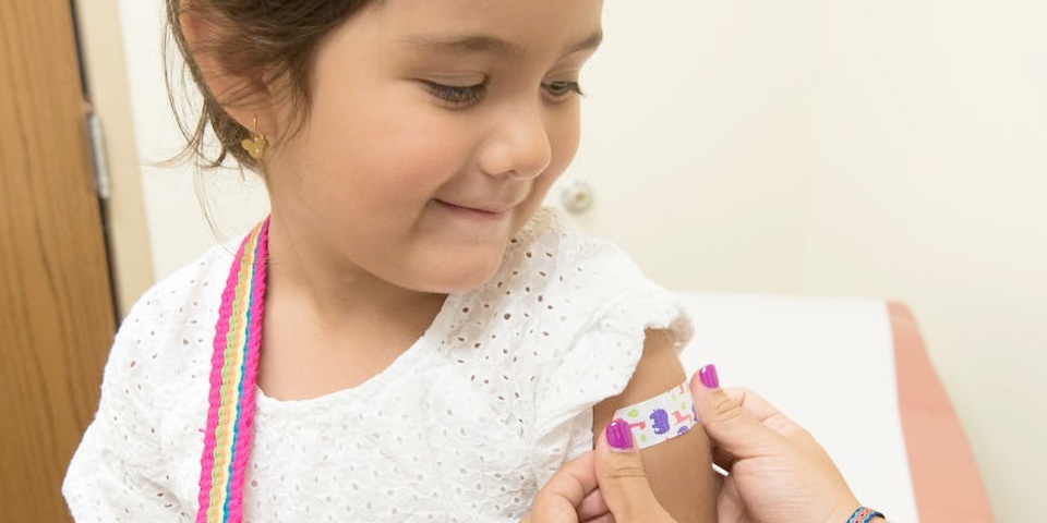 young girl receiving jab sticker