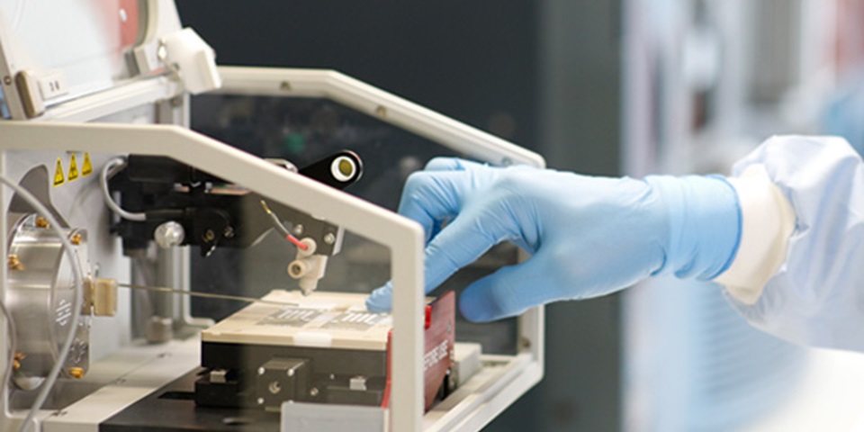 close up of gloved researcher hand in lab machine