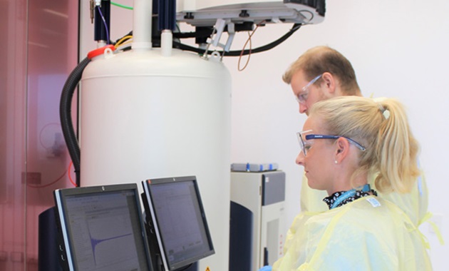 Understanding the pathways to infection and the biological consequents of COVID-19 two researchers in yellow lab coats looking at monitors
