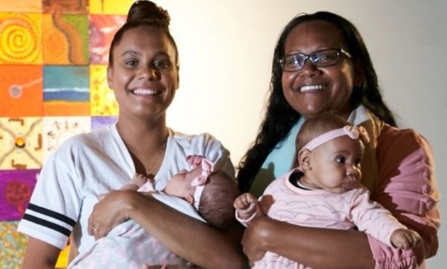 women holding two babies
