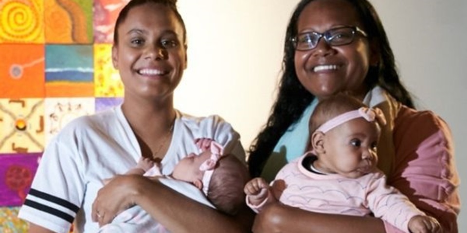 women holding two babies