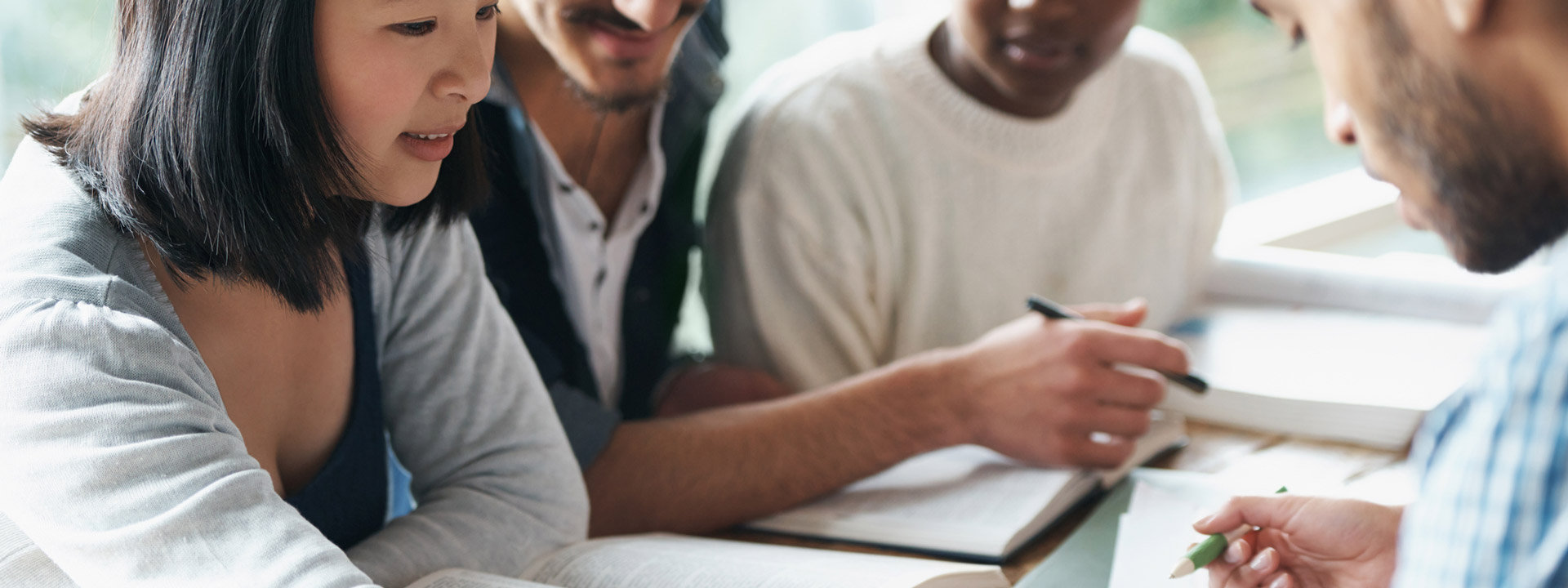 Four professional workers looking at the same document and looking like they're trying to solve a problem together.