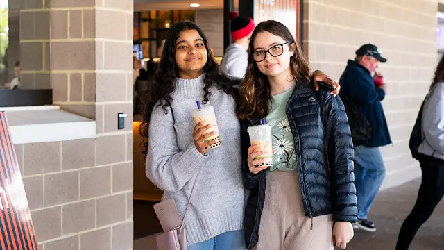 2 students with bubble tea outside Student Hub