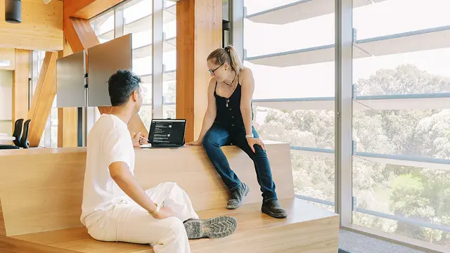 2 students looking at laptop in open learning area