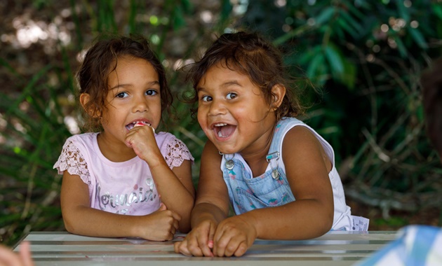 Two little girls at a table outside together