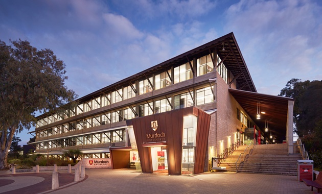 Murdoch's main building on the South St campus at dusk, with brights lights still on and trees in the background.