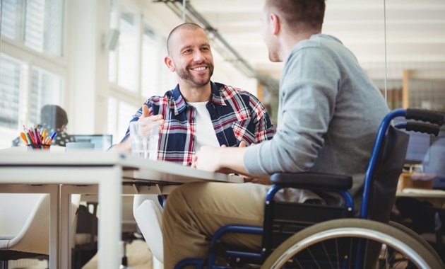 Two male students talking. One of them is in a wheelchair.