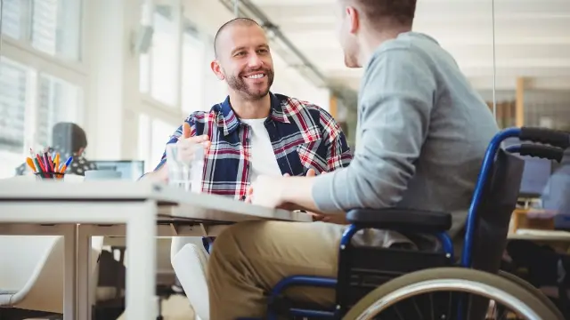 Two male students talking. One of them is in a wheelchair.