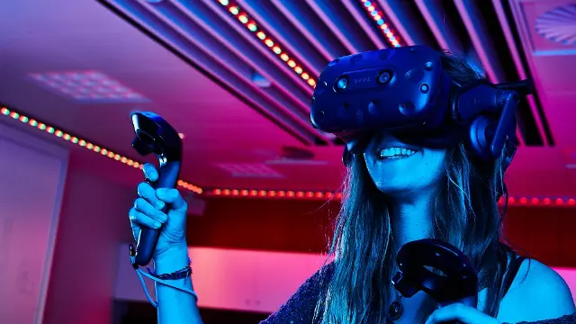 A female student wearing a VR headset and holding gaming controls.