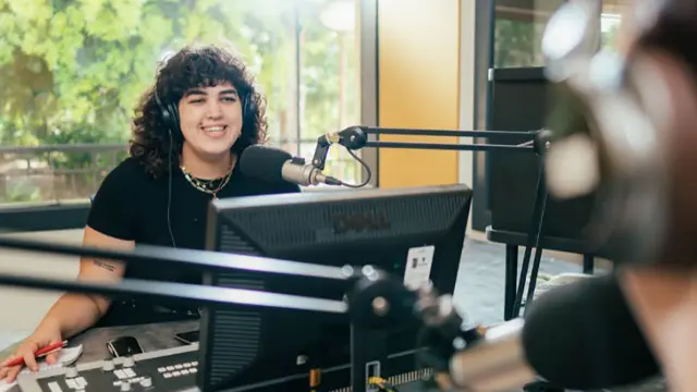 Media and communications student in recording studio with microphone