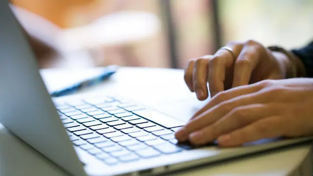 Students taking notes and working on laptops in a tutorial