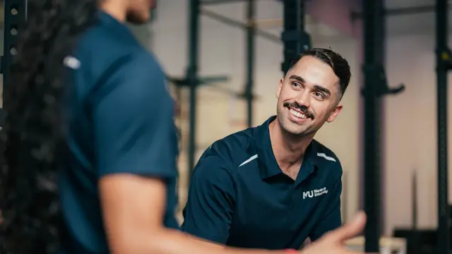 Allied health student smiling in a gym or rehabilitation facility