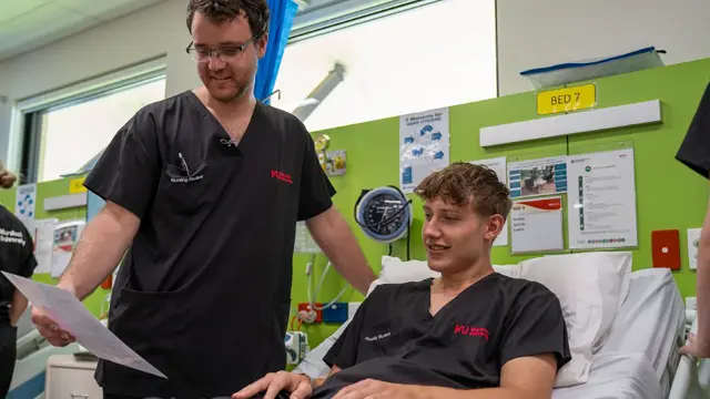 Nursing student and lecturer reviewing information at a patient bedside
