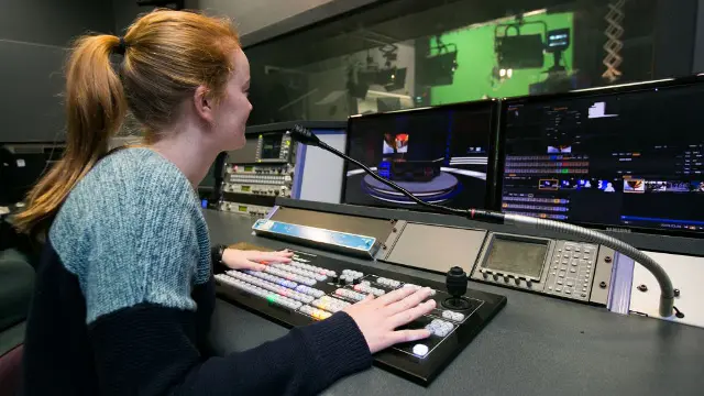 Media student operating a video editing suite with multiple screens