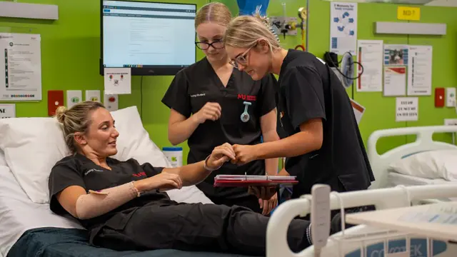 Nursing students assisting a patient in a clinical simulation ward