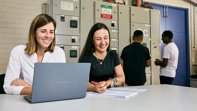 Students working on laptops in a campus study space