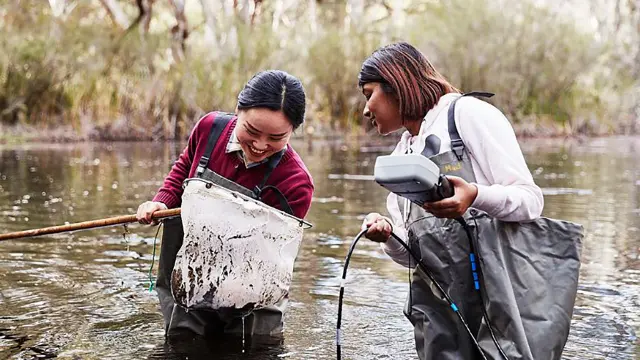 Environmental and conservation sciences students in a lake with net and measuring device