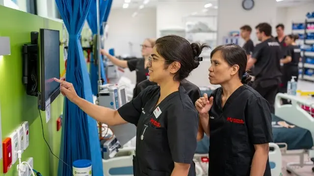 Murdoch Nursing students referring to a screen in the on-campus nursing wards