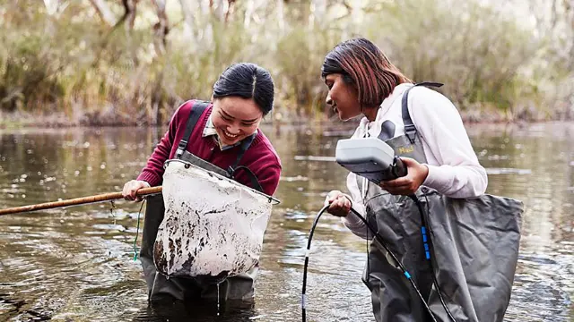 Environmental and conservation sciences students in a lake with net and measuring device