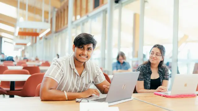 Students collaborating on laptops in a campus study area