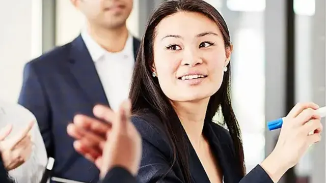 Business students wearing suits writing on whiteboard