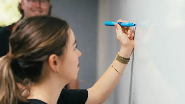 Education student writing on a whiteboard during a tutorial