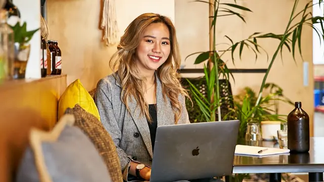 Student working on a laptop in a relaxed campus setting