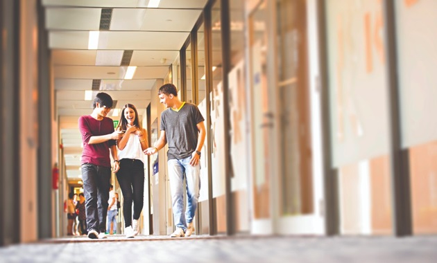 Three students walking together inside the Singapore campus.