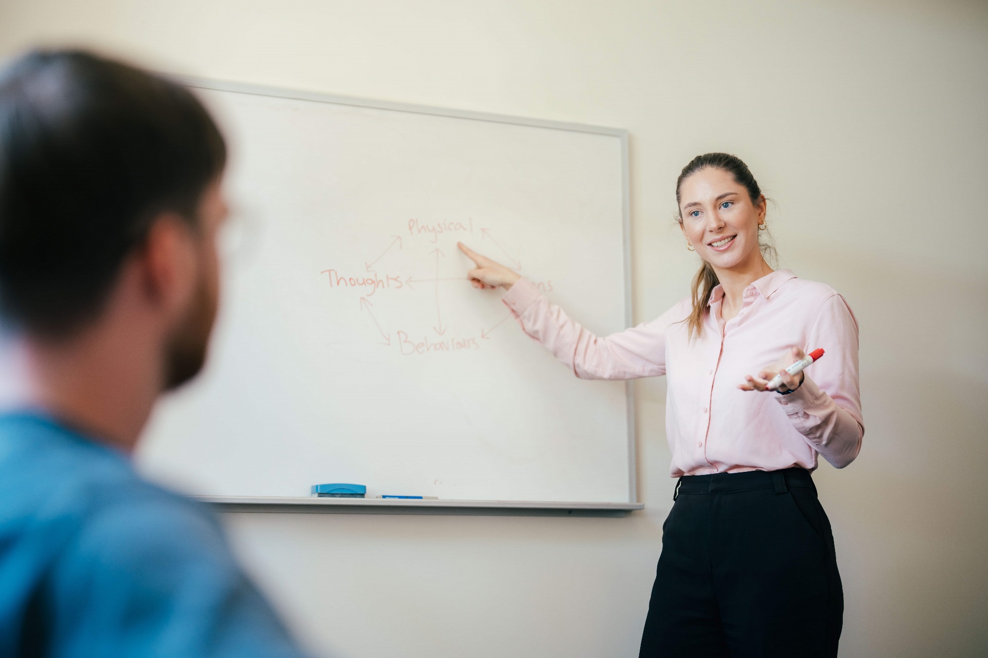Female psychologist pointing at whiteboard to teach student