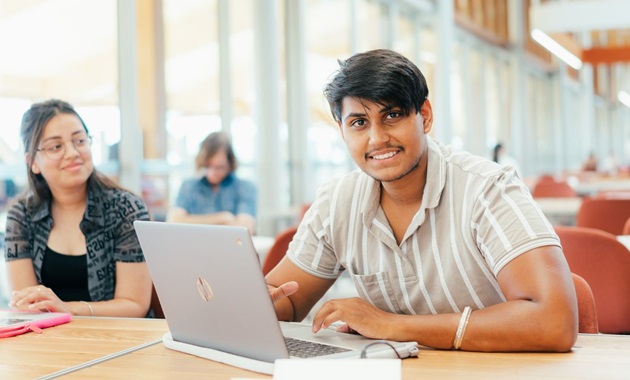 Two students on their laptops inside Boola Katitjin