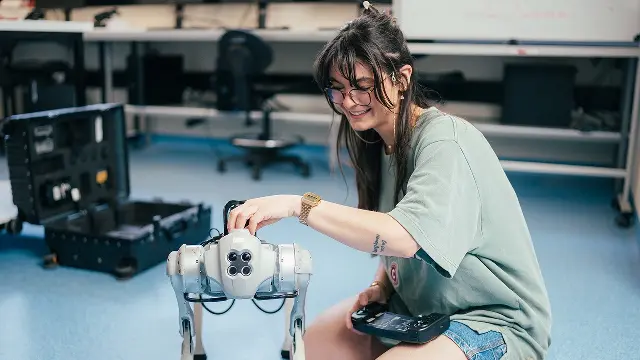 Murdoch University engineering student inspecting robotic dog