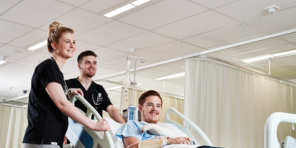 Nursing students with patient on bed