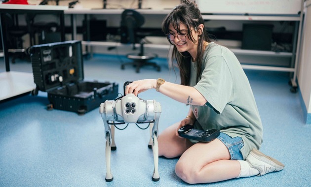 Female engineering student smiling as she works on a robot