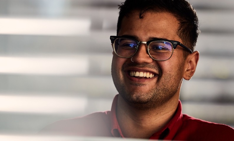 A male business student in an office smiling.