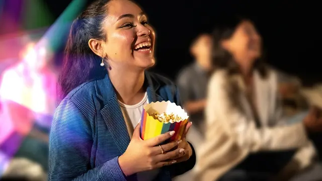 A woman sits with a bucket of popcorn at the community cinema