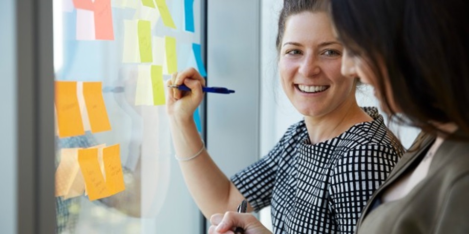 Women writing on post it note on window