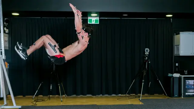 Man in mid-air doing a backflip in the performance lab.