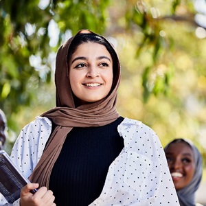 Image of international student smiling, holding textbooks