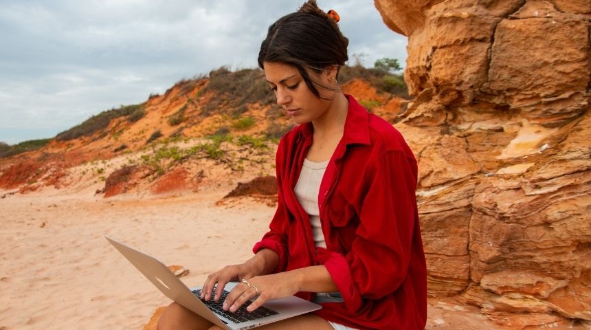 Karis sitting outside at the beach in Broome on her laptop