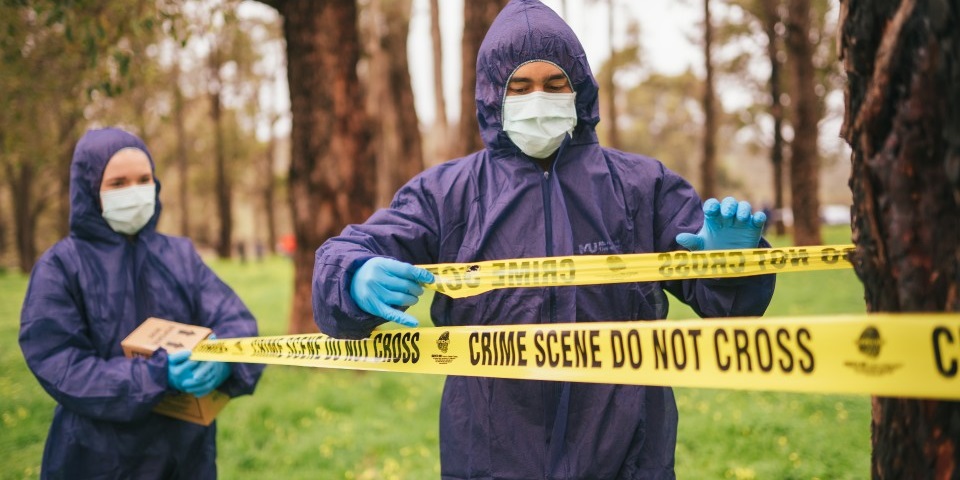 Students taping off a crime scene with crime scene tape