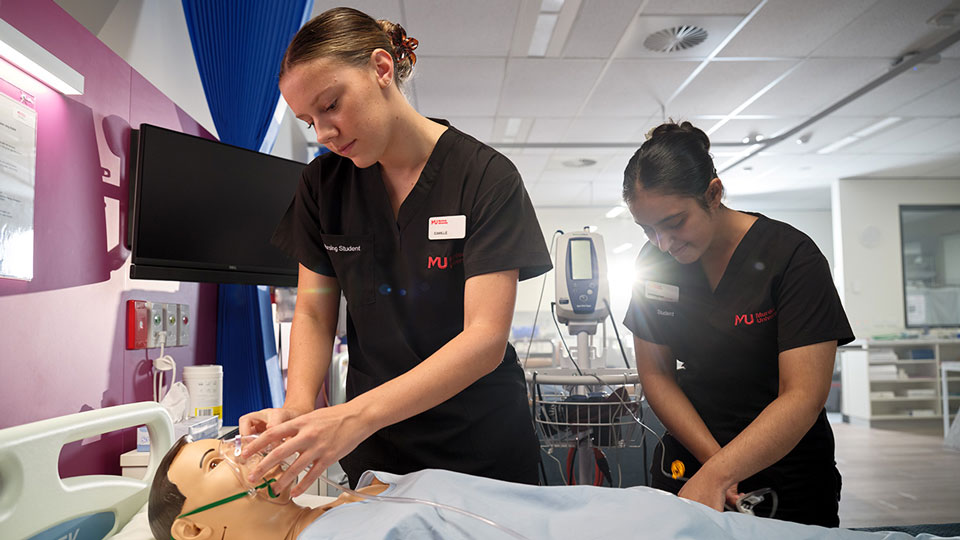 Two Murdoch nursing students practising clinical skills on a simulation mannequin in the on-campus ward