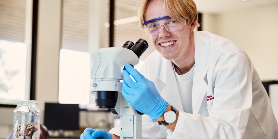 Male student looking over the top of a microscope