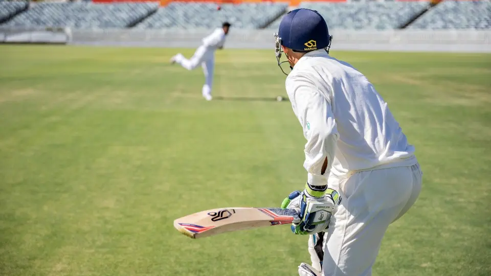Cricketer Mike Hussey batting against a young bowler.