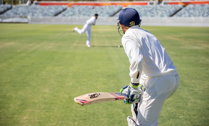 Cricketer Mike Hussey batting against a young bowler.