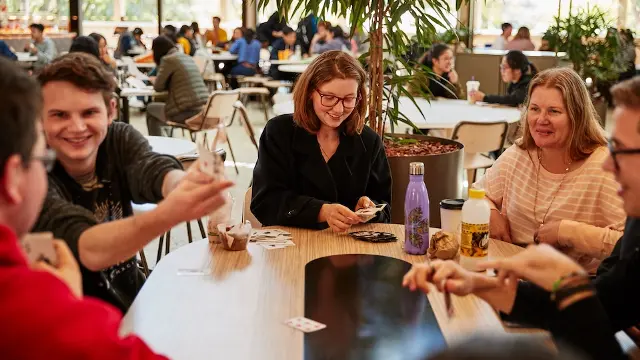 Staff and students playing cards in Student Hub