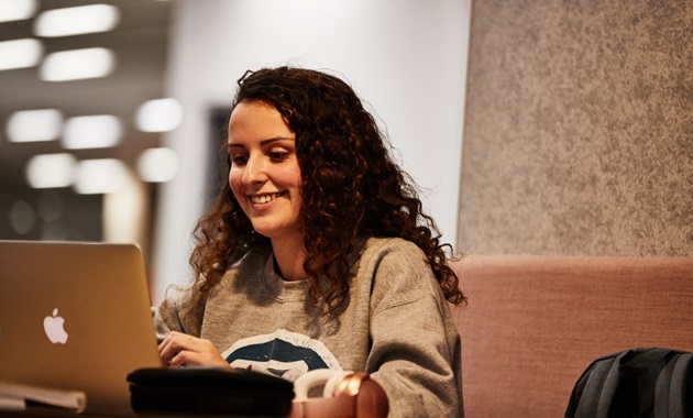 A female student working on a laptop in the Murdoch Library.