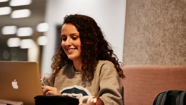 A female student working on a laptop in the Murdoch Library.