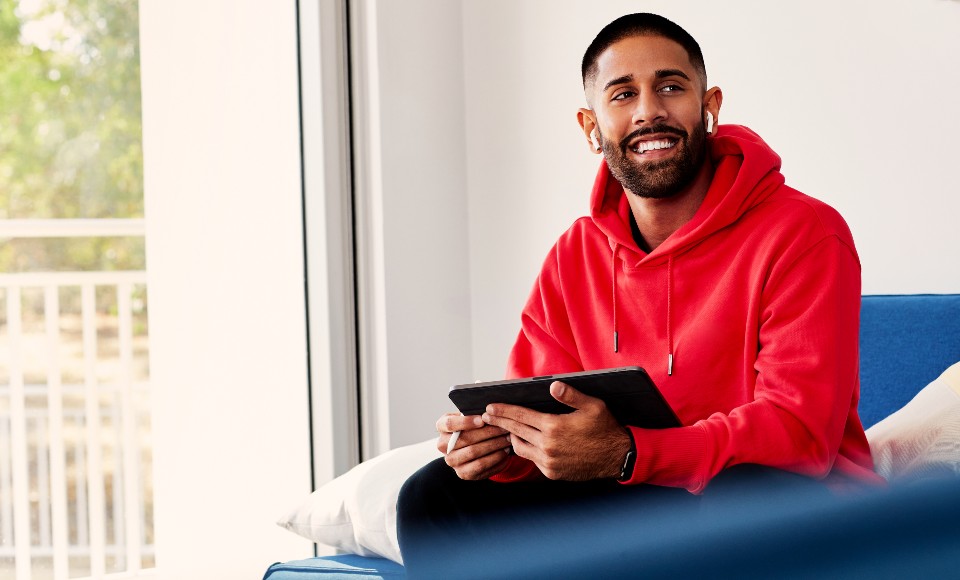 Murdoch student sitting on a couch with a tablet in his hands.