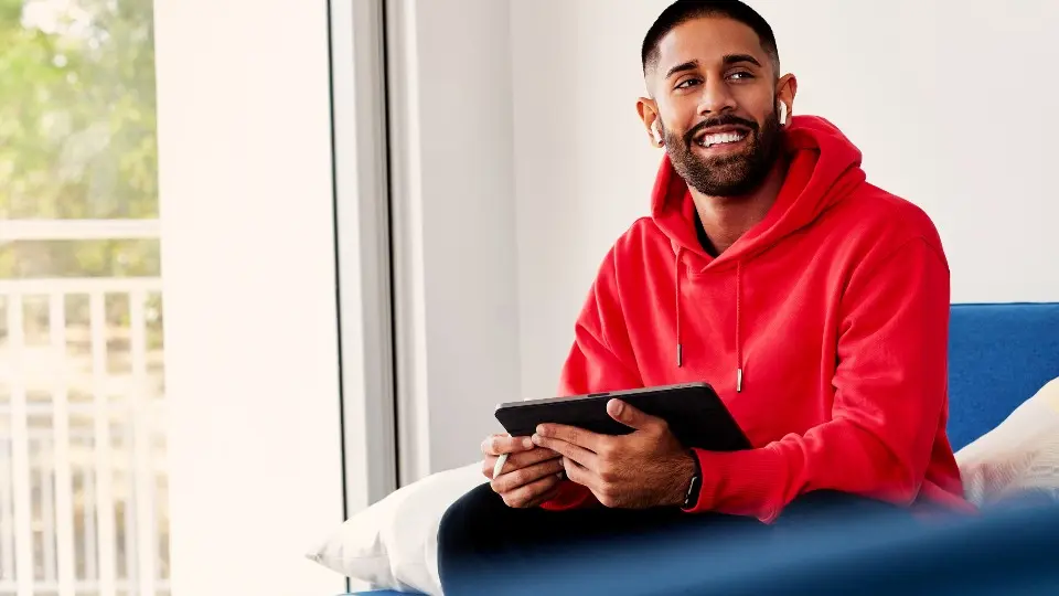 Murdoch student sitting on a couch with a tablet in his hands.